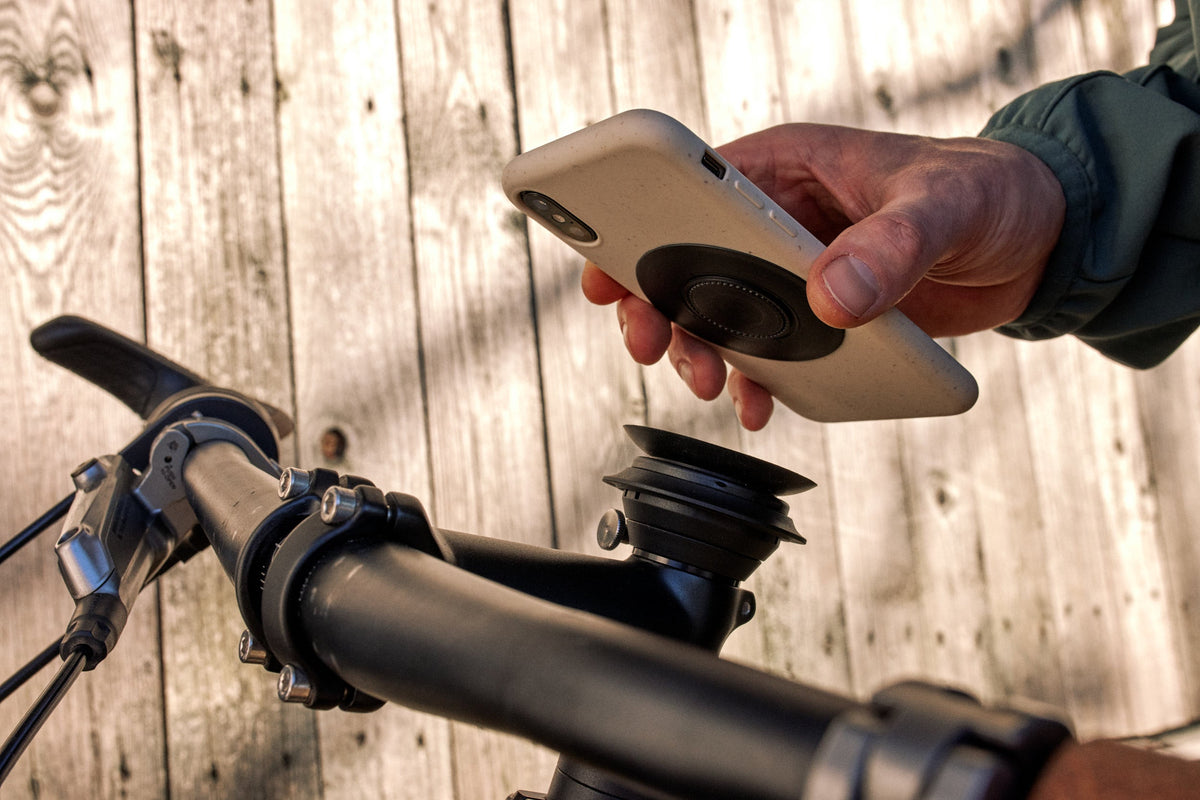 Parche FIDLOCK VACUUM para smartphone universal negro — parche negro colocado en el teléfono, frente a un soporte VACUUM